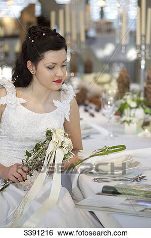 Bride sitting at a table, looking in a magazine View Large Photo Image Stock Photograph - Bride sitting at a table, looking in a magazine . Fotosearch