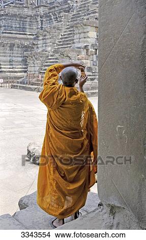Buddhist monk looking at mobile phone, Angkor, Cambodia, rear view View Large Photo Image Picture - Buddhist monk looking at mobile phone, Angkor, Cambodia, rear view . Fotosearch