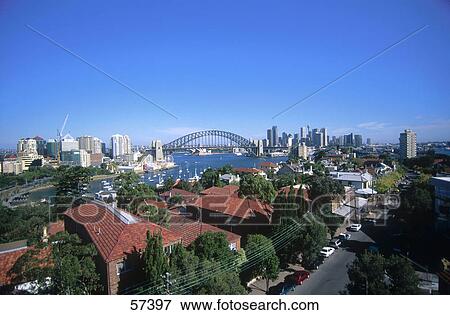 Stock Photo - Buildings in city with bridge in background, Sydney Harbor Bridge, Sydney Harbor, Sydney, New South Wales, Australia . Fotosearch