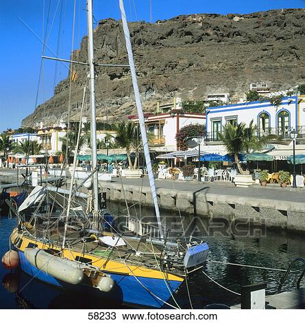 Stock Image - Close of a sailboat with houses in the background, Puerto de Mogan, Gran Canaria, Canary Islands, Spain . Fotosearch