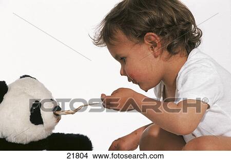 Picture - Close-up of a baby feeding a teddy bear . Fotosearch