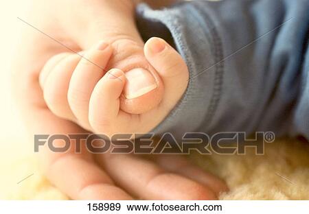Stock Photo - Close-up of baby holding mother's thumb . Fotosearch