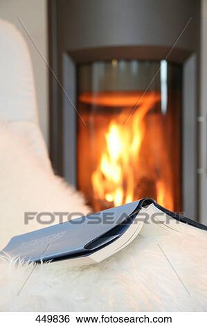 Stock Photograph - Close-up of book on couch with fireplace in background . Fotosearch