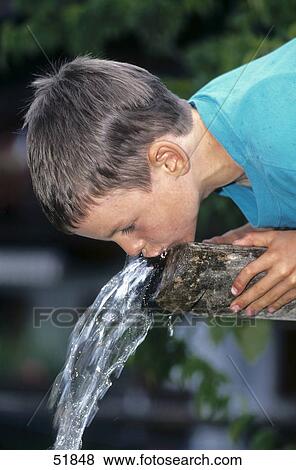 Stock Photo - Close-up of boy drinking water from well . Fotosearch