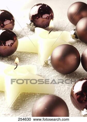 Stock Image - Close-up of Christmas ornaments and star shape lit candles . Fotosearch