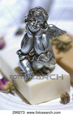 Stock Image - Close-up of figurine of angel on bar of soap . Fotosearch