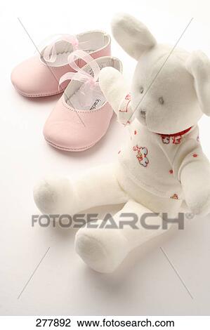 Stock Image - Close-up of pair of baby booties and teddy bear . Fotosearch