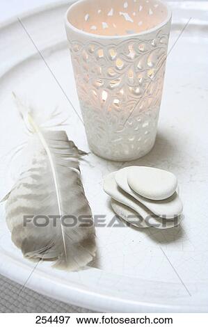 Stock Photo - Close-up of pebbles and feather with lamp on tray . Fotosearch