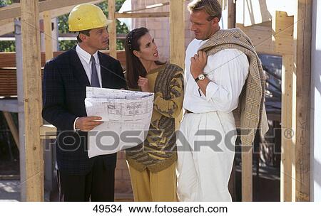 Picture - Couple standing with architect at construction site . Fotosearch