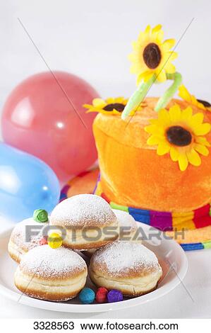 Stock Image - Doughnuts, colourful hat and toy balloons, high angle view . Fotosearch