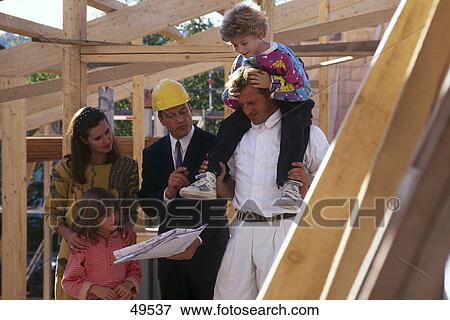 Stock Photo - Family standing with architect at construction site . Fotosearch