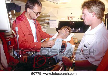 Stock Photo - First aid doctor helping patient on stretcher . Fotosearch