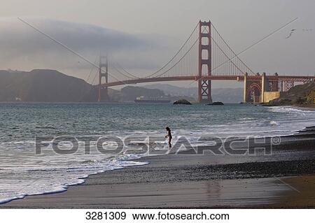 Stock Photo - Girl playing at beach in front of Golden Gate Bridge, San Fransisco, California, USA . Fotosearch