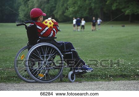 Picture - Handicapped child holding soccer ball in wheelchair . Fotosearch