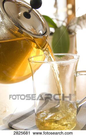 Stock Image - Herbal tea being poured into cup . Fotosearch
