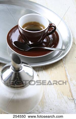 Stock Image - High angle view of cup of black coffee and sugar shaker . Fotosearch