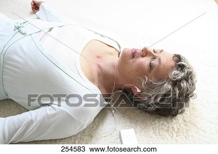 High angle view of senior woman listening to MP3 player View Large Photo Image Stock Image - High angle view of senior woman listening to MP3 player . Fotosearch