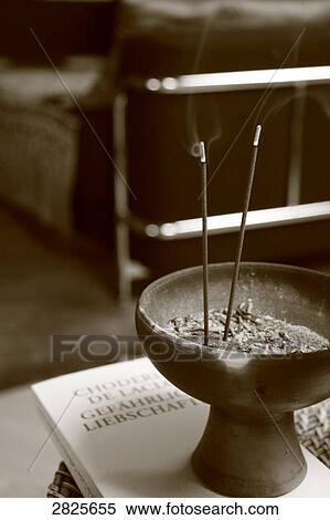 Stock Photography - Incense burning in decorative urn on book . Fotosearch