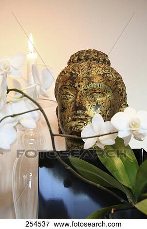 Stock Photo - Low angle view of statue of Buddha and flowers . Fotosearch
