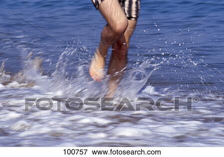Low section view of man running in water on beach View Large Photo Image Stock Photo - Low section view of man running in water on beach . Fotosearch