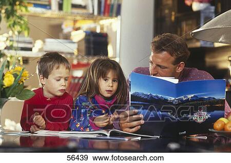 Stock Photo - Man and his children reading books in living room . Fotosearch