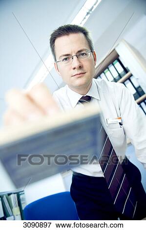 Stock Photo - Man holding a stamp towards camera, facing camera, low angle view, close-up . Fotosearch