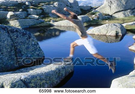 Man jumping across river on rocks, Norway View Large Photo Image Stock Photo - Man jumping across river on rocks, Norway . Fotosearch
