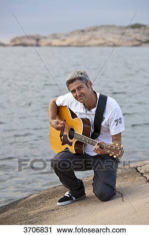 Man playing guitar at the skerry coast in Sotenaes, Sweden View Large Photo Image Stock Image - Man playing guitar at the skerry coast in Sotenaes, Sweden . Fotosearch