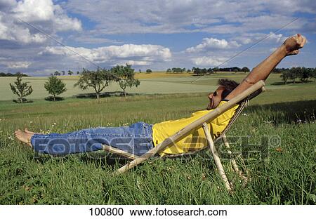 Man sitting in deck chair, side view View Large Photo Image Stock Image - Man sitting in deck chair, side view . Fotosearch