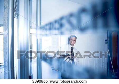 Man with files standing behind a closed glass door, facing camera View Large Photo Image Stock Photography - Man with files standing behind a closed glass door, facing camera . Fotosearch