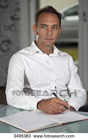 Stock Image - Man with notepad sitting at a table . Fotosearch
