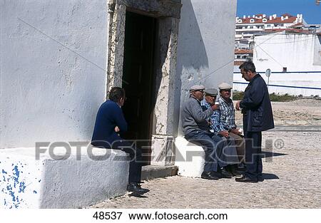 Stock Photo - Men talking in front of house, Ericeira, Estremadura, Portugal . Fotosearch