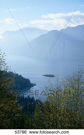 Stock Photograph - Mountains in fog at lakeside, Lake Garda, Monte Baldo, Veneto, Italy . Fotosearch