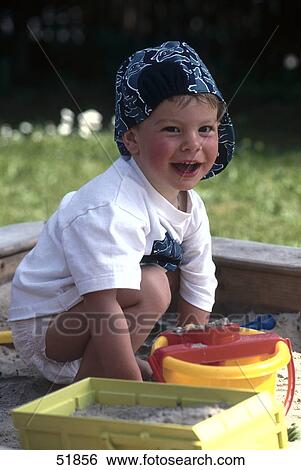 Stock Photograph - Portrait of boy playing with toys in sandpit . Fotosearch
