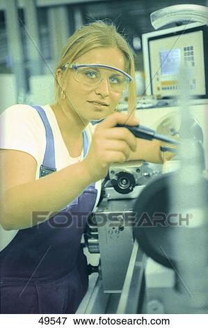 Stock Photo - Portrait of young woman using lathe machine . Fotosearch