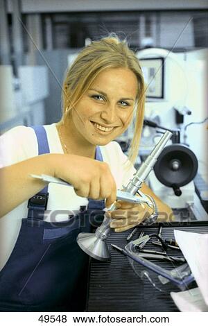 Stock Photo - Portrait of young woman using vernier caliper and smiling . Fotosearch