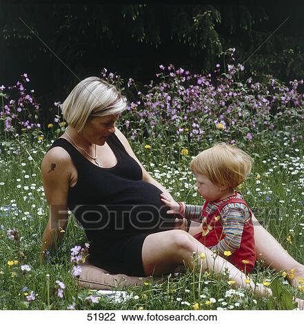 Pregnant woman and child sitting on meadow View Large Photo Image Stock Image - Pregnant woman and child sitting on meadow . Fotosearch