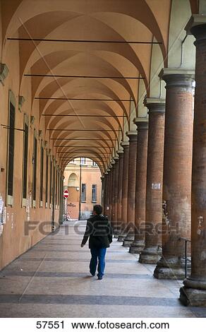 Stock Image - Rear view of a man walking in colonnade, University of Bologna, Emilia-Romagna, Italy . Fotosearch