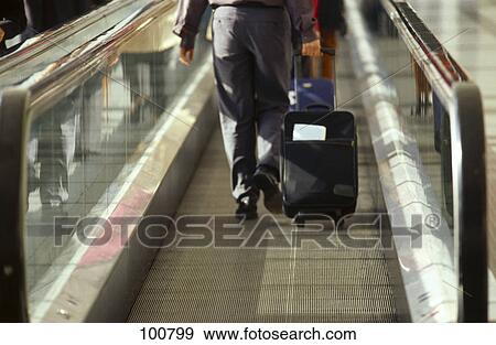Stock Photo - Rear view of businessman pulling his suitcase at airport . Fotosearch
