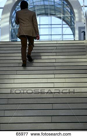 Rear view of businessman walking upstairs View Large Photo Image Stock Photo - Rear view of businessman walking upstairs . Fotosearch