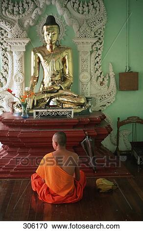 Stock Image - Rear view of monk praying in temple, Shwedagon Pagoda, Yangon, Myanmar . Fotosearch