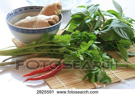 Stock Image - Red chilli pepper with herbs and ginger on mat . Fotosearch