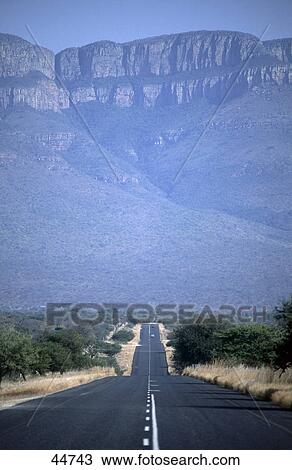 Stock Image - Road leading towards mountain, Drakensberg, South Africa . Fotosearch