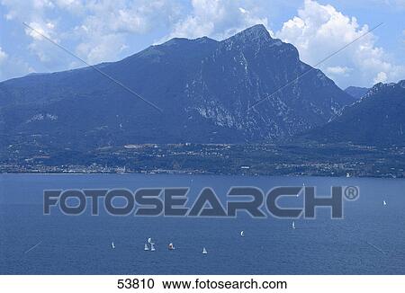 Sailboats in lake in front of mountains, Lake Garda, Veneto, Italy View Large Photo Image Stock Image - Sailboats in lake in front of mountains, Lake Garda, Veneto, Italy . Fotosearch