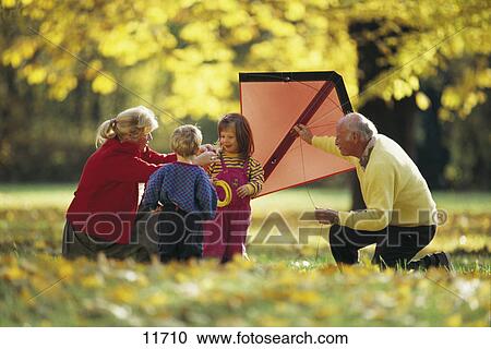 Stock Image - Senior couple playing with their grandchildren in a park . Fotosearch