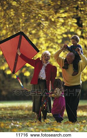 Stock Photograph - Senior couple playing with their grandchildren in a park . Fotosearch