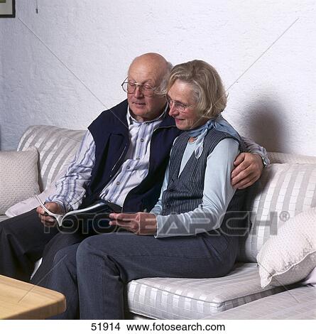 Senior couple reading book on couch View Large Photo Image Picture - Senior couple reading book on couch . Fotosearch