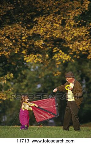 Senior man helping his grandchild to fly a kite in a park View Large Photo Image Stock Image - Senior man helping his grandchild to fly a kite in a park . Fotosearch