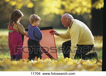 Senior man playing with his grandchildren in a park View Large Photo Image Picture - Senior man playing with his grandchildren in a park . Fotosearch