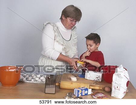 Stock Image - Senior woman and her grandson preparing cookies in kitchen . Fotosearch